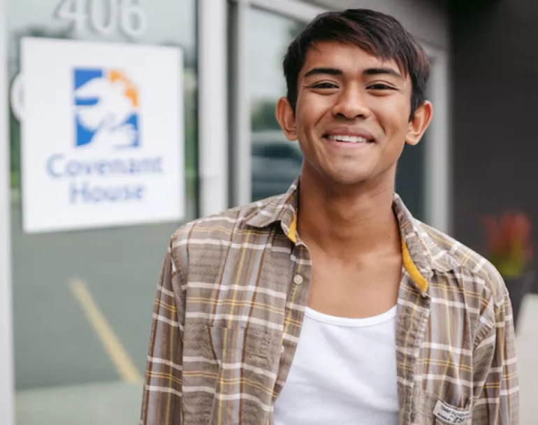 Former homeless teen smiling in front of Covenant House site | Donate Today