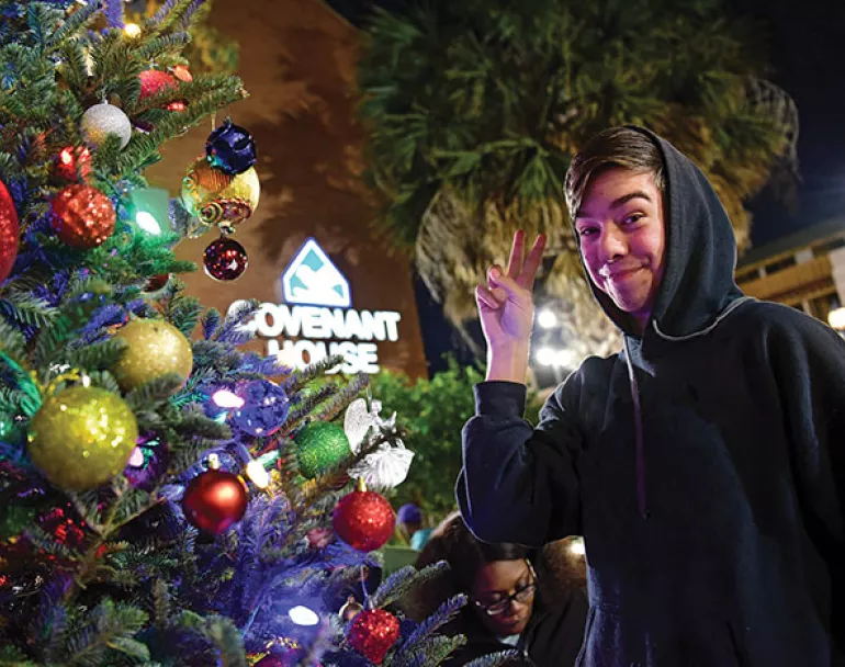 Former homeless teen next to Christmas tree and in front of Covenant House site