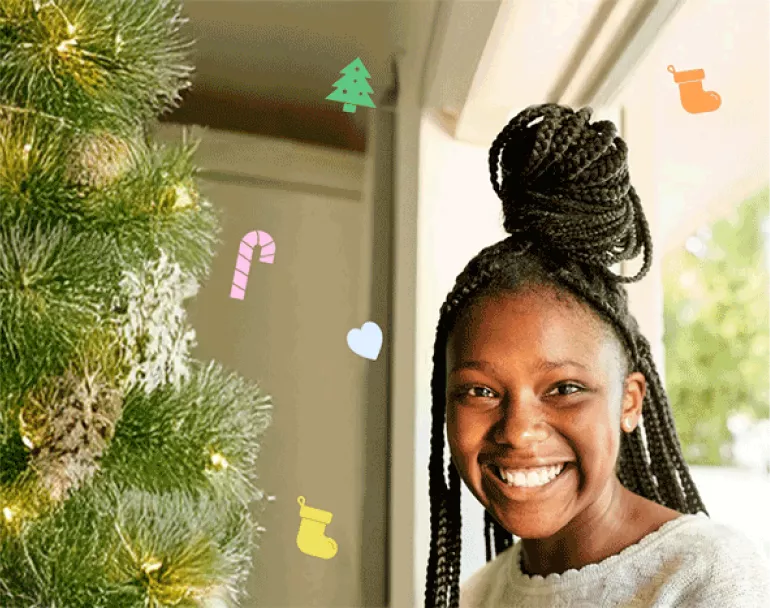 previously homeless teen next to Christmas tree | Covenant House - Donate Now to Help Homeless Youth This Holiday Season