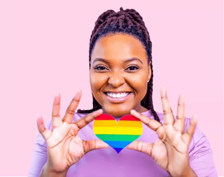 homeless girl holding up a pride heart | Covenant House - Donate today to help LGBTQ+ homeless youth
