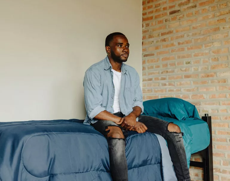 former homeless youth sitting on bed | Covenant House - Affordable Housing