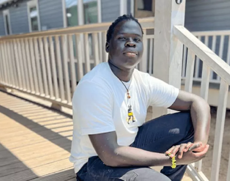 Former homeless youth sitting on house porch | Covenant House - Donate now 