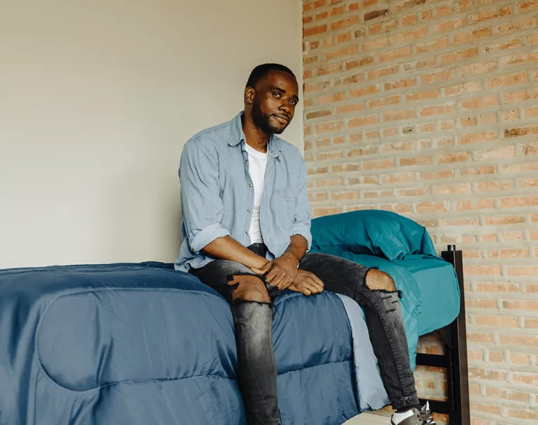 former homeless youth sitting on bed | Covenant House - Affordable Housing