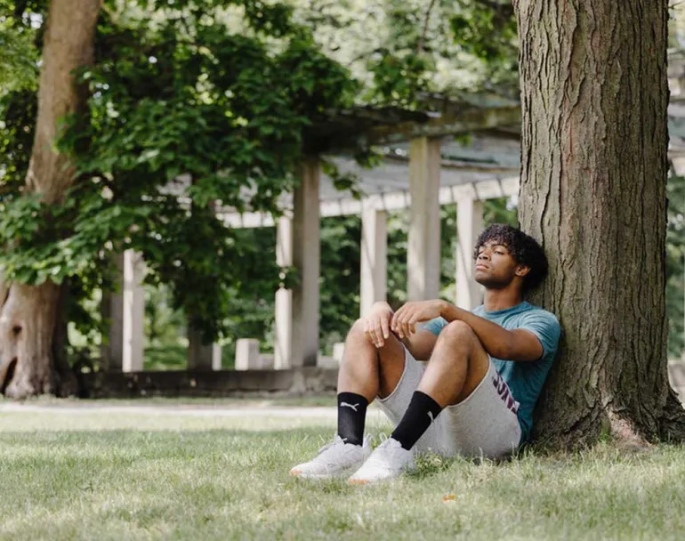 homeless youth sitting against a tree 