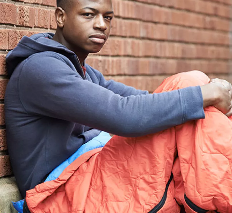 Teen in sleeping bag leaning against wall