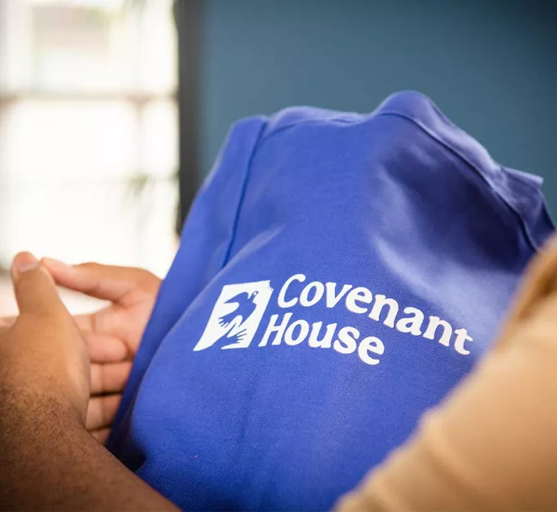 homeless youth holding tote bag gift from Covenant House | Workplace Giving - Employee Giving - Employee Giving Programs