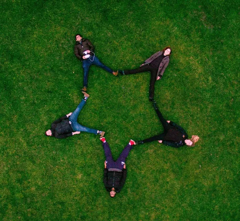 former homeless teens forming a star while lying down on grass | Covenant House - DIY Fundraise