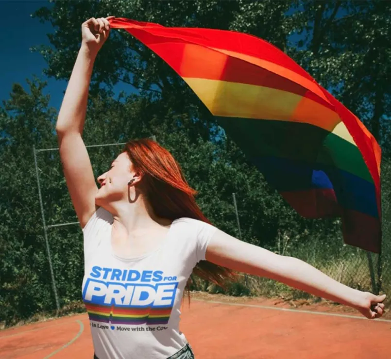 LGBTQ+ youth with pride flag and Strides for Pride shirt | Covenant House